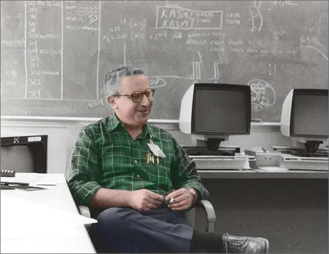 Seymour Sack sitting in front of a chalkboard with equations