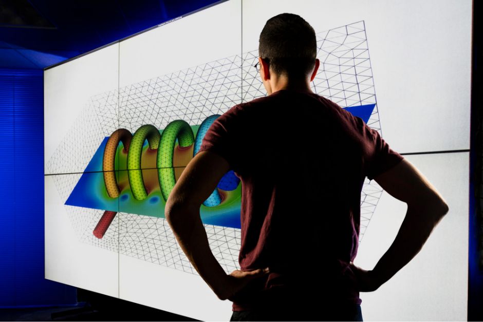 scientist standing in front of a large screen viewing a simulation
