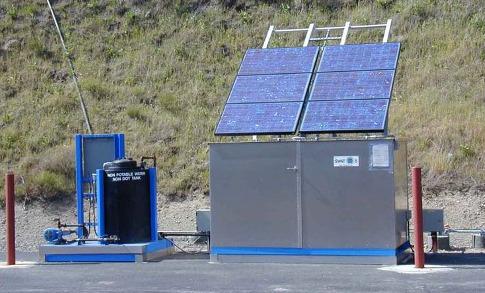Solar panel with stainless steel cabinet and black tank/device on top of concrete foundation
