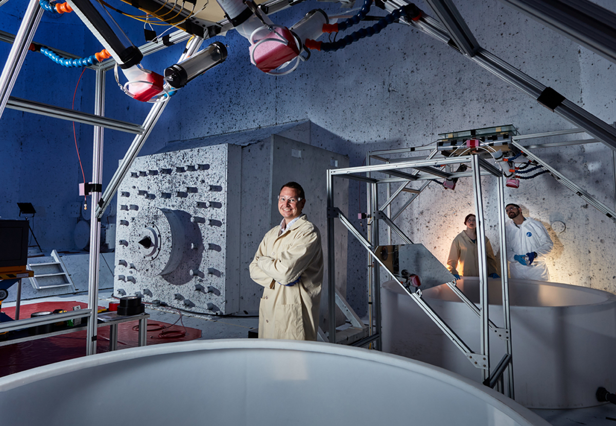 Person in lab suit standing in front of equipment.
